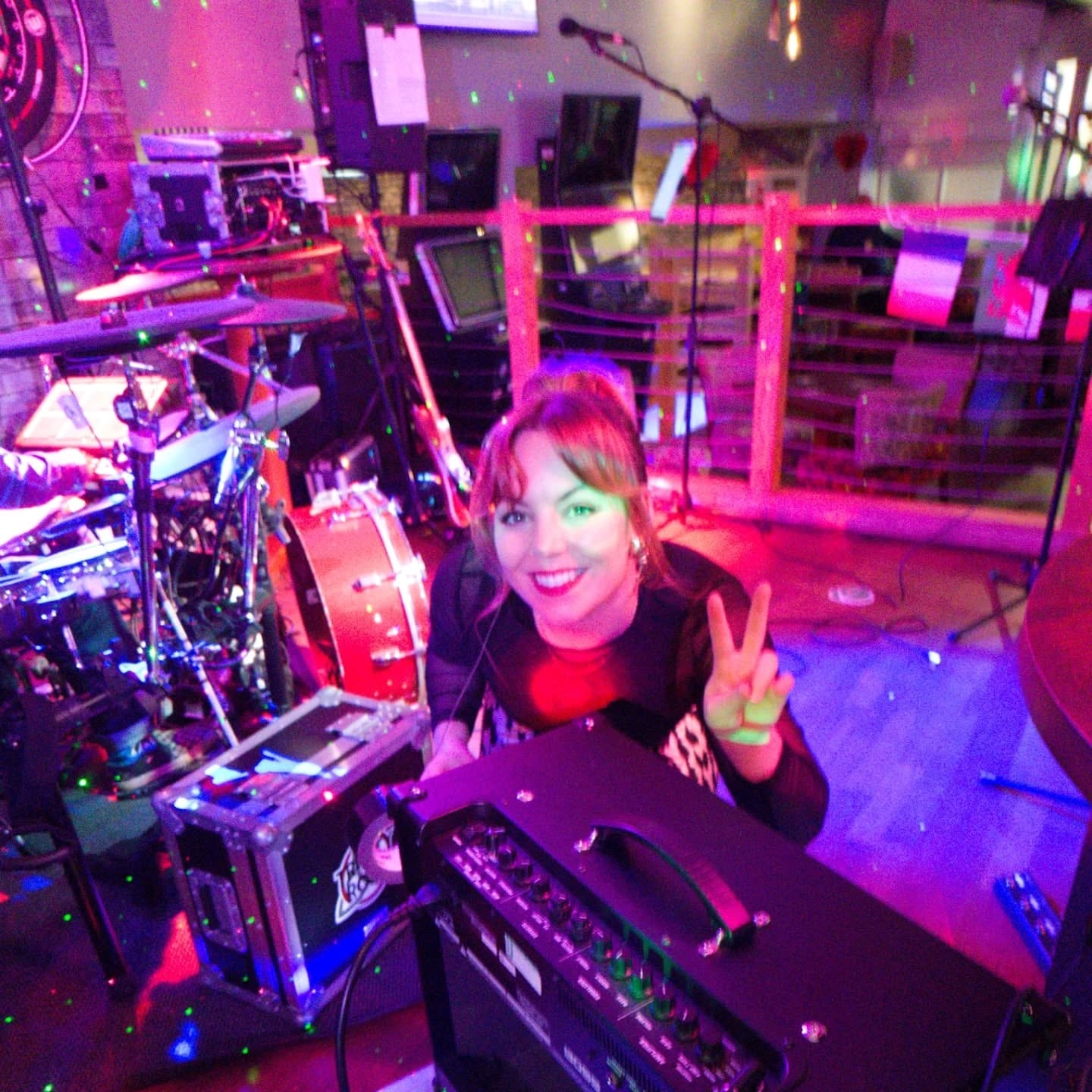 Vocalist selfie on stage with drum kit and laser lights behind