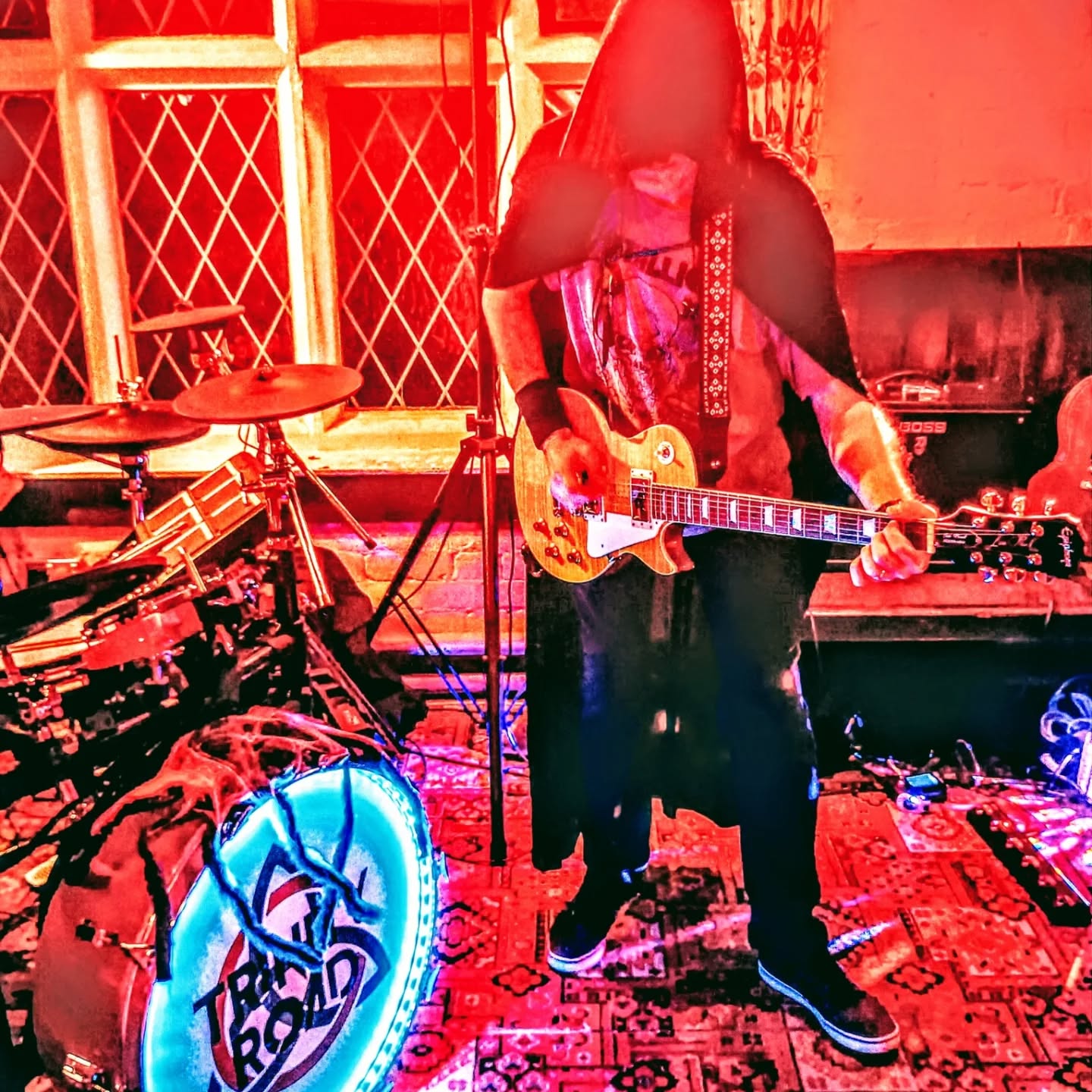 Guitarist playing a Les Paul under dramatic red stage lighting